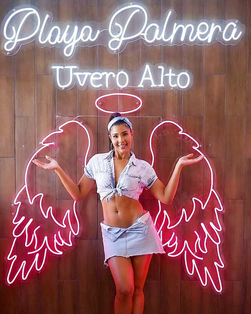 Woman in front of Playa Palmera's neon sign at Heladeria Yummy